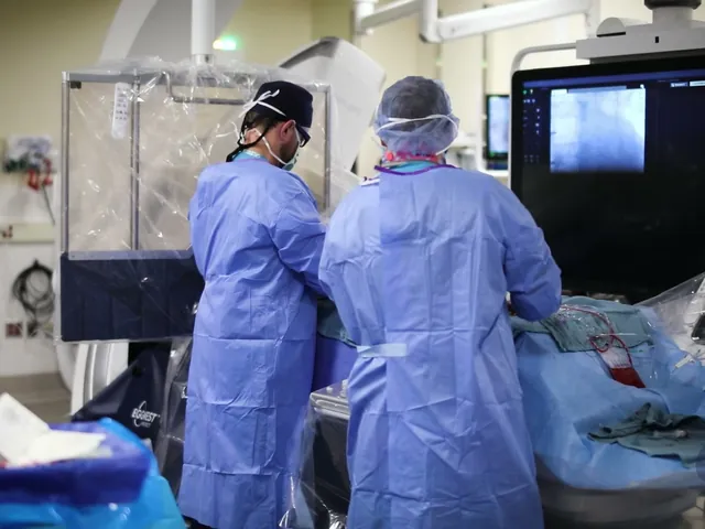 Two gowned clinicians at the procedure table in a cath lab with EggNest Complete, its clear shield beside them