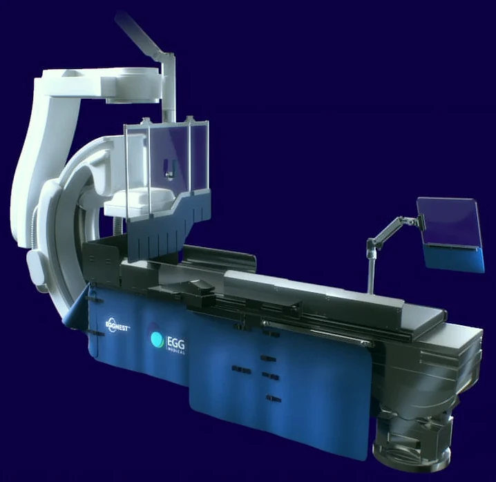 The EggNest system on a cath lab table beside the C-arm, with its upper shields raised
